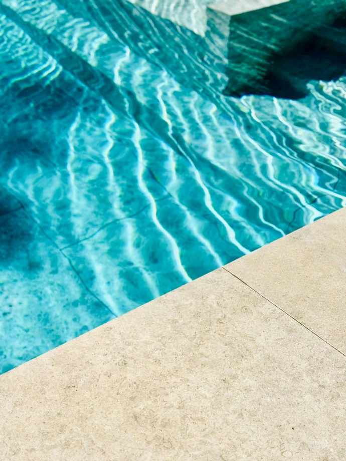 Sunlight reflects on clear blue swimming pool water.